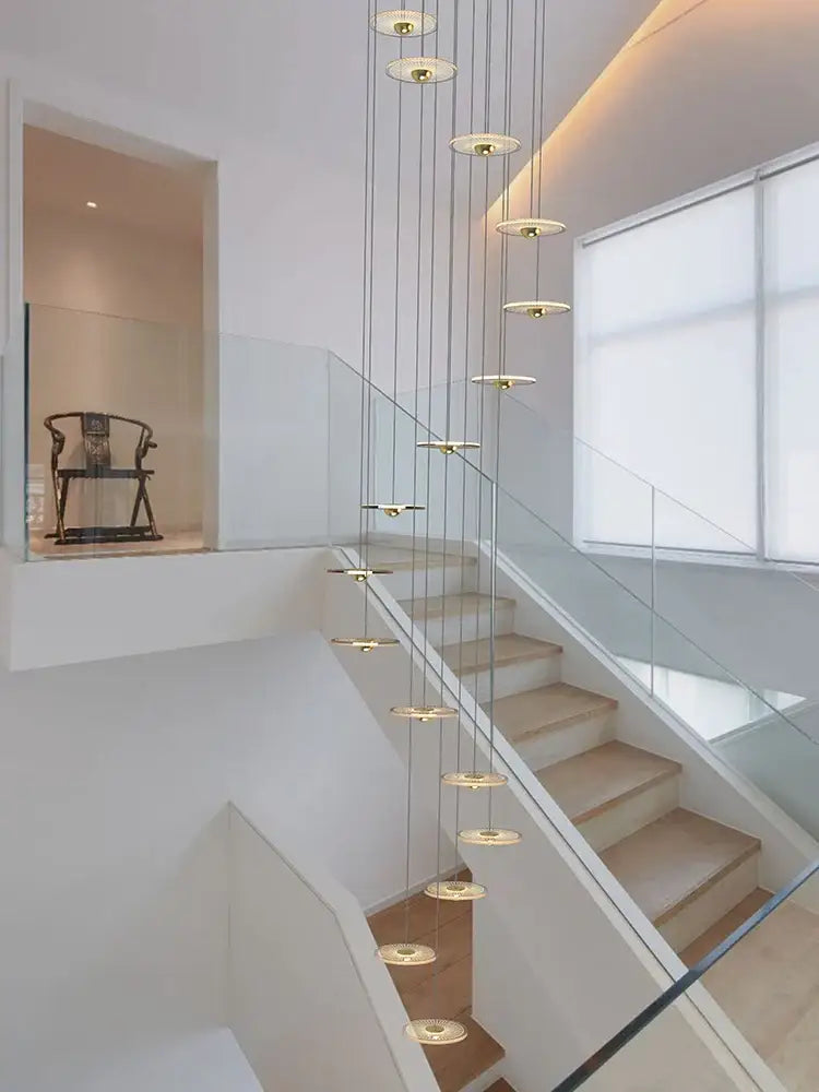 Modern minimalist decorbites led chandelier with gold-toned circular discs cascading from thin cables for staircase use