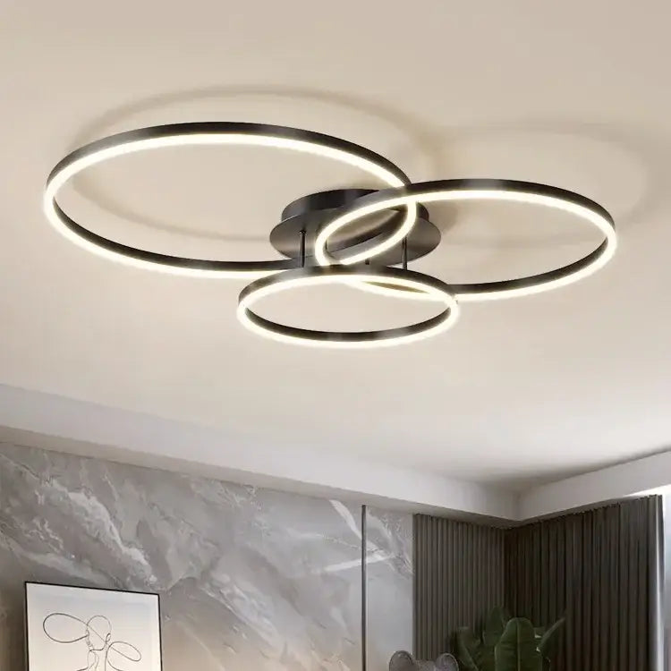 Modern black circular decorbites led chandelier with three interlocking rings emitting warm glow for bedroom lighting