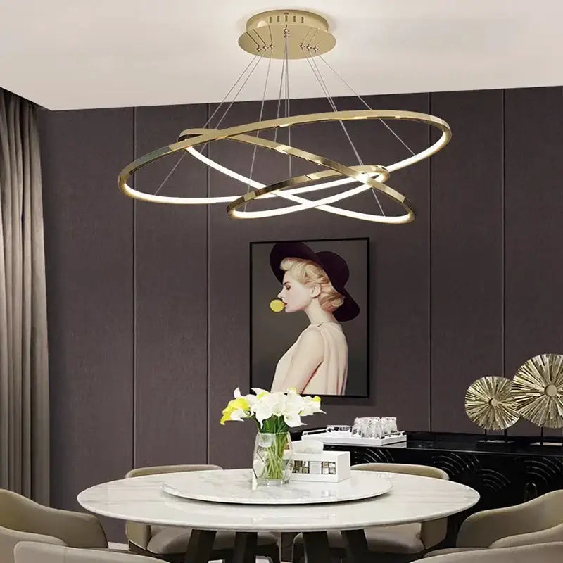 Modern gold-toned decorbites led chandelier pendant with circular intersecting rings above dining table lighting