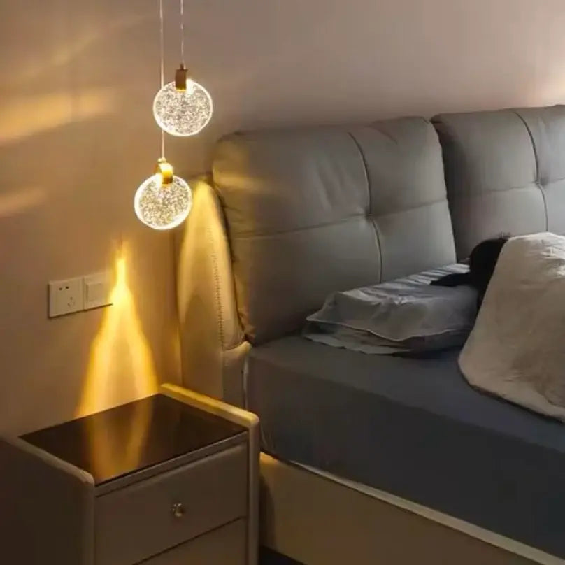 Two clear glass decorbites™ led crystal pendant lights with golden metal fixtures for bedroom and bathroom use
