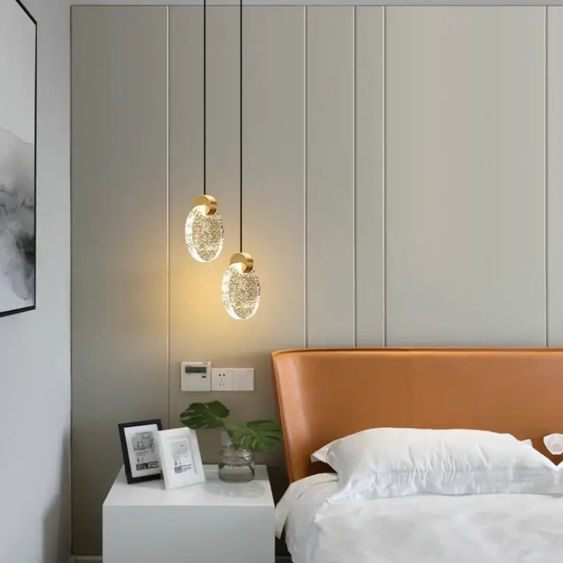Two elegant decorbites™ led crystal pendant lights with gold fixtures and crystal glass bodies hang above a bed