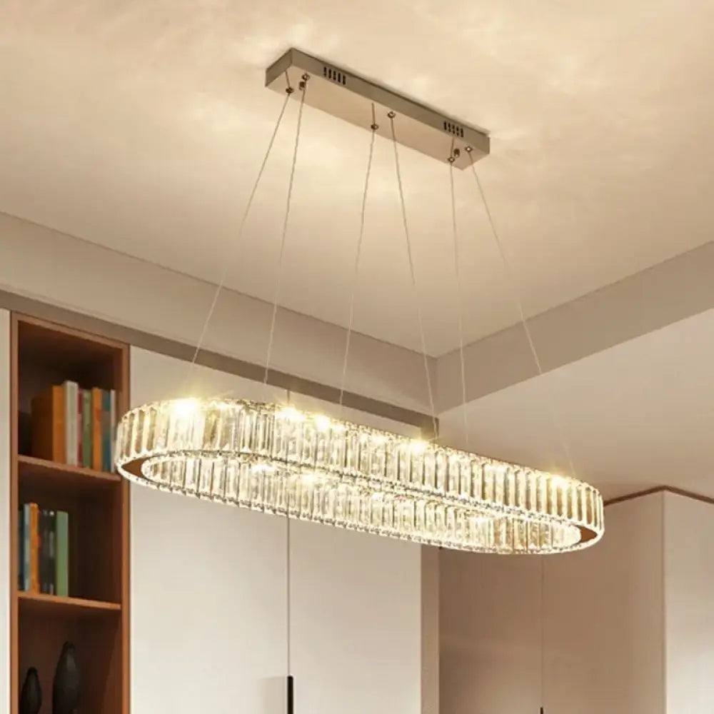 A modern oval stainless steel ceiling light with clear crystal tiers refracting light for restaurant use