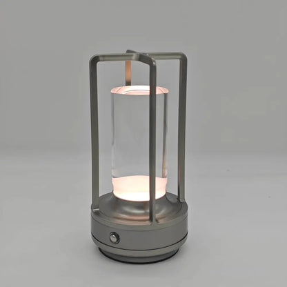 A sleek silver metallic frame led crystal table lamp with clear glass and rechargeable touch light for bedside use