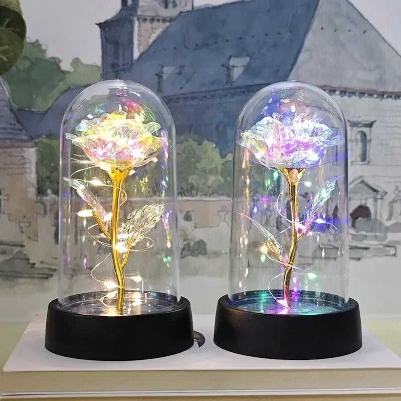 Two illuminated decorbites™ eternal rose lights with golden stems and glowing led lights casting rainbow hues