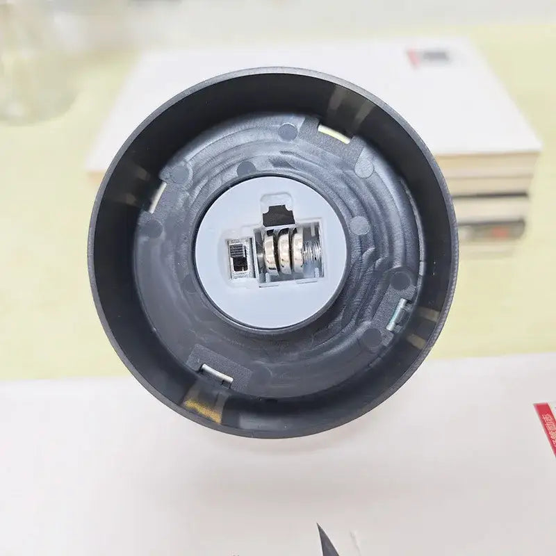 Black plastic flashlight head with internal battery compartment and metal spring mechanism for DecorBites™ eternal rose light