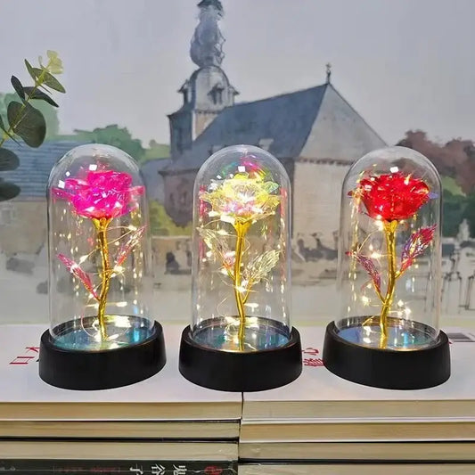 Three illuminated glass-domed eternal rose lights with golden stems and glowing led lights for valentine’s day and weddings