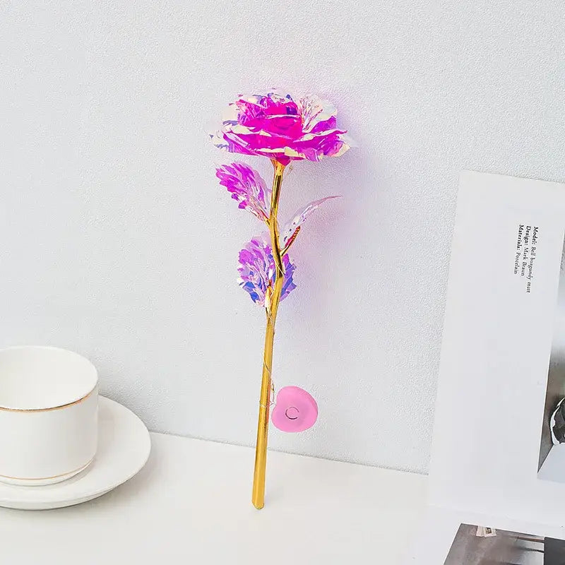 A vibrant pink and purple metallic DecorBites™ eternal rose light with a golden stem and translucent petals for weddings