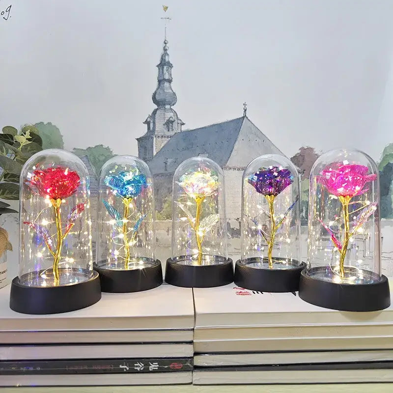 Five glittering illuminated eternal rose lights with golden stems under glass domes on black bases for weddings and valentines day