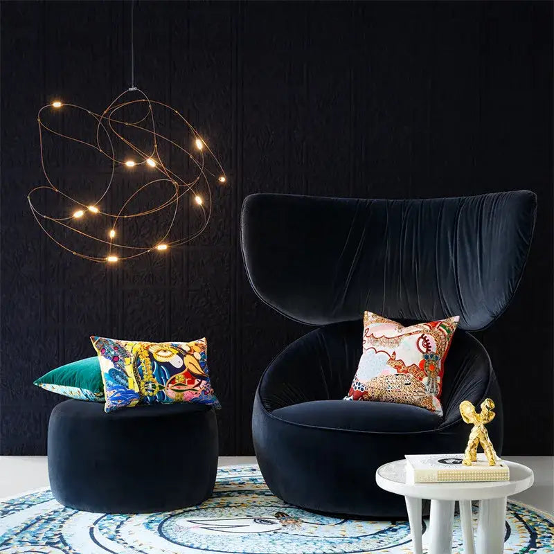 Black velvet armchair with high curved back and plush seating paired with decorbites led firefly chandelier for hotel and kitchen
