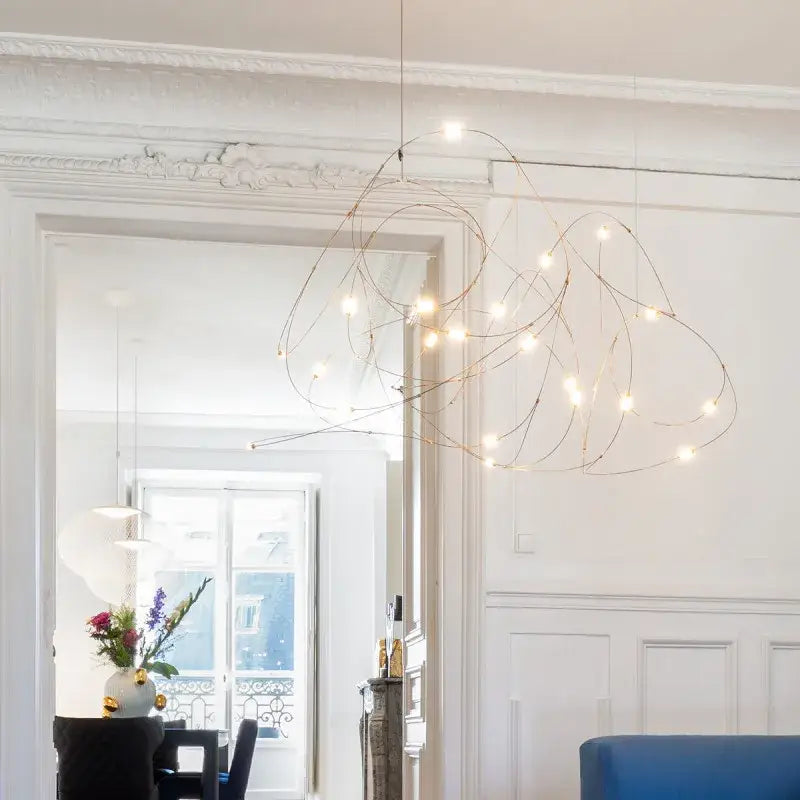 A modern decorbites led firefly chandelier with a gold-toned wireframe and warm-white bulbs in an engineering minimal design