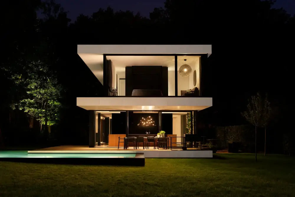 Modern two-story white house with black framed glass walls and glowing pool featuring decorbites led firefly chandelier engineering minimal design