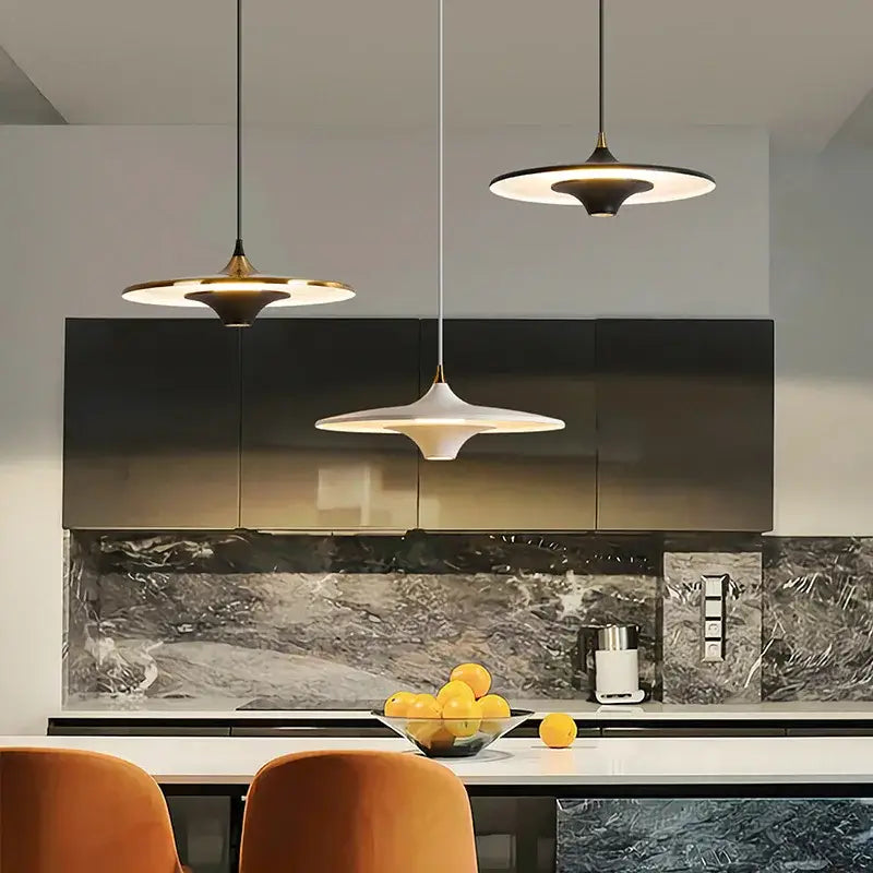 Three decorbites led flying saucer pendant lights with white and gold disc-shaped shades hang above a kitchen island