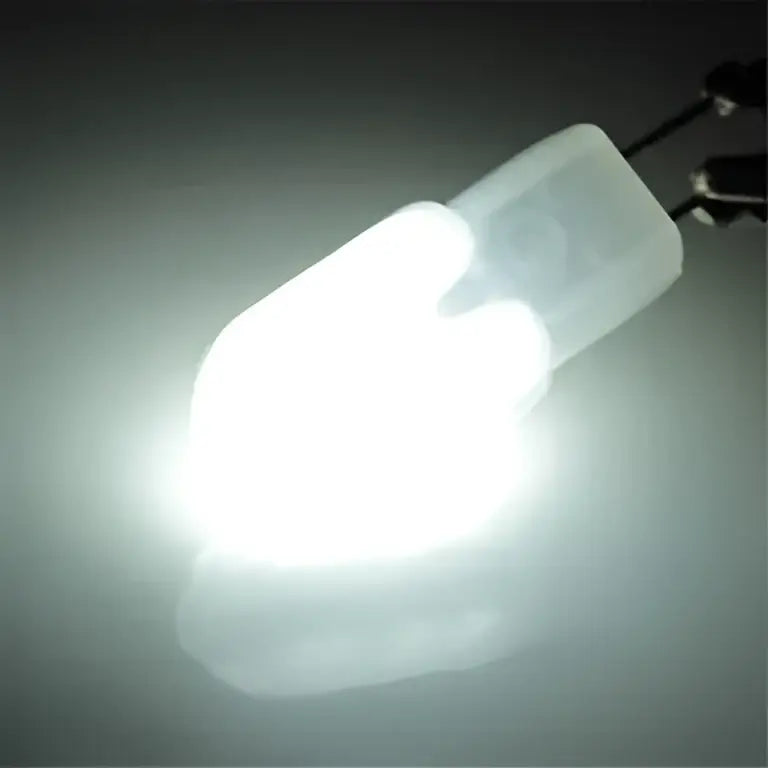 A bright white decorbites led g4 bulb with translucent frosted plastic housing and metallic bi-pin contacts at the base