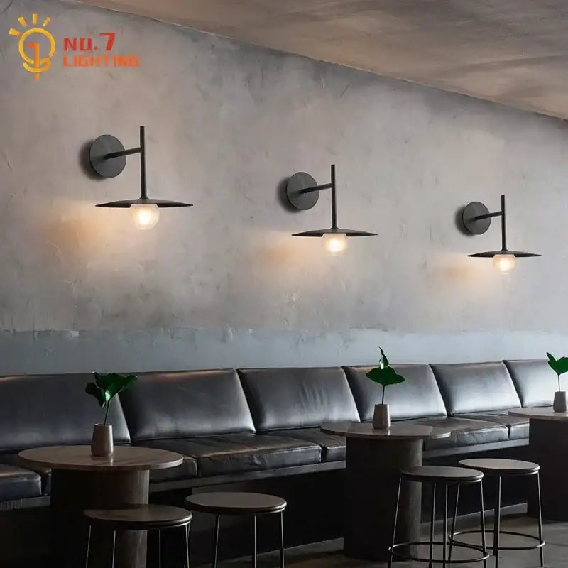 Three black metal decorbites led g9 wall lamps with flat shades emitting warm glow for living room and cafe decor