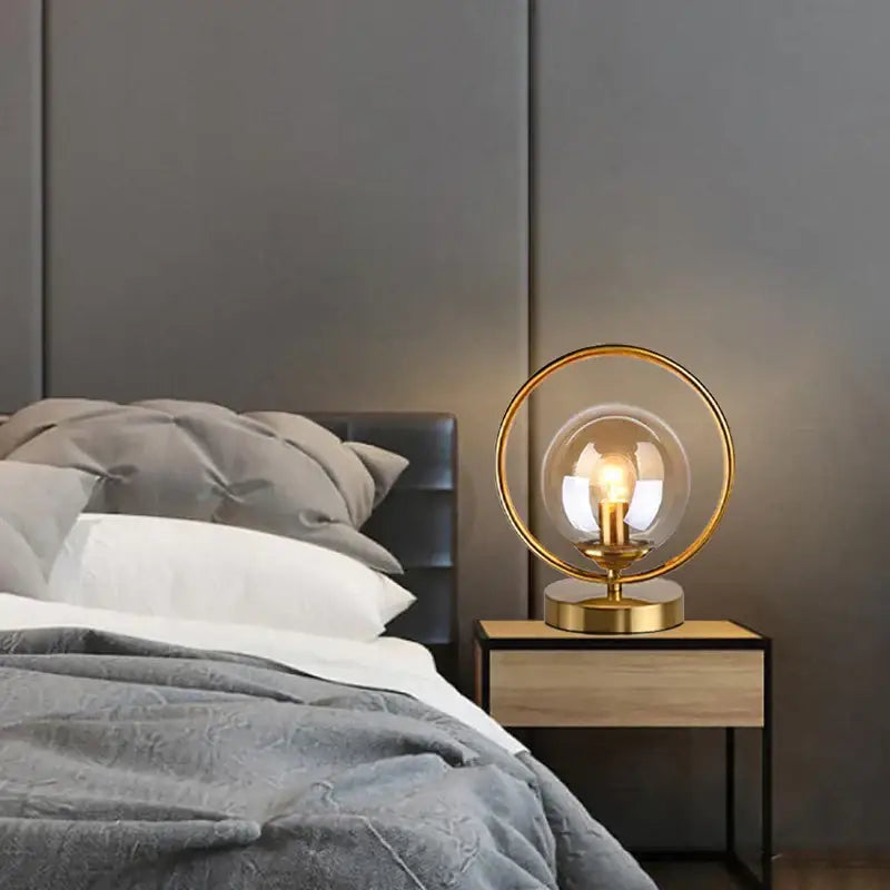 Gold-toned table lamp with brass ring base featuring decorbites led glass globe and exposed filament bulb for stylish lighting