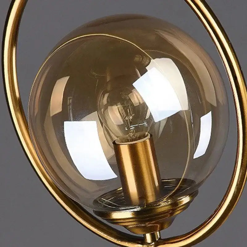 Gold-toned decorbites led glass table lamp with brass ring and clear globe housing exposed filament bulb for stylish lighting