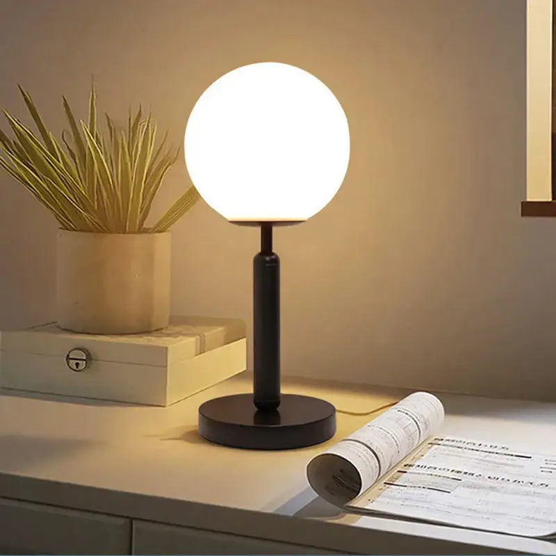 A sleek black table lamp featuring a glowing led glass ball shade by DecorBites led glass for luxury decor