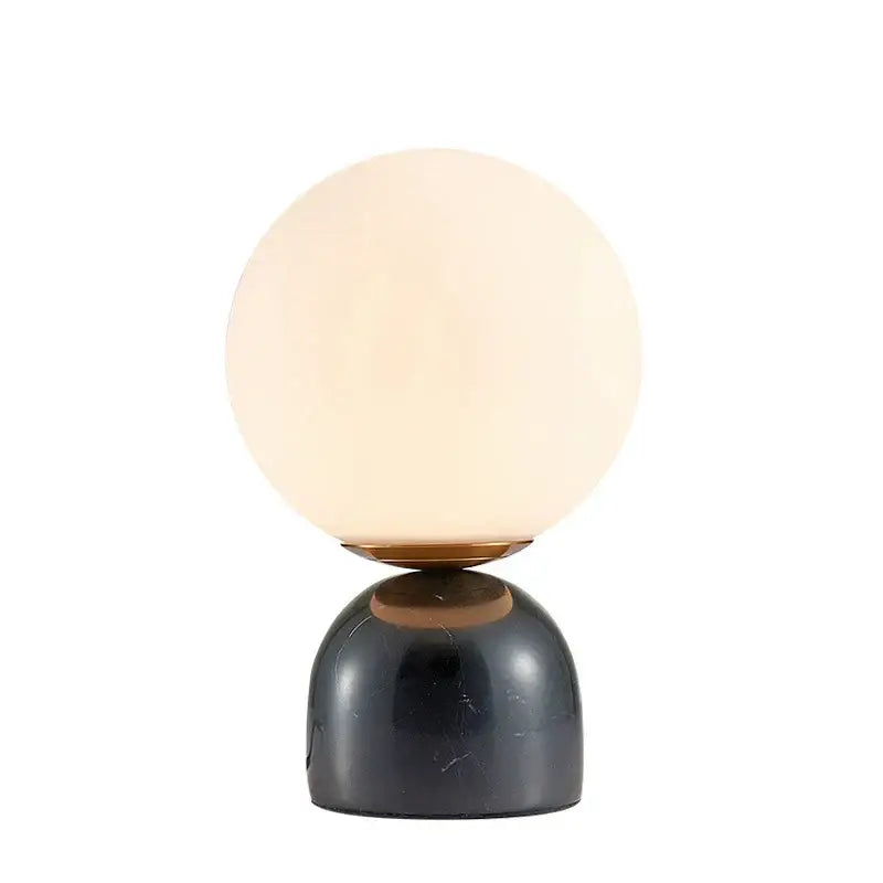 A sleek black marble base supports a warm frosted glass globe with brass accent in DecorBites LED glass ball table lamp