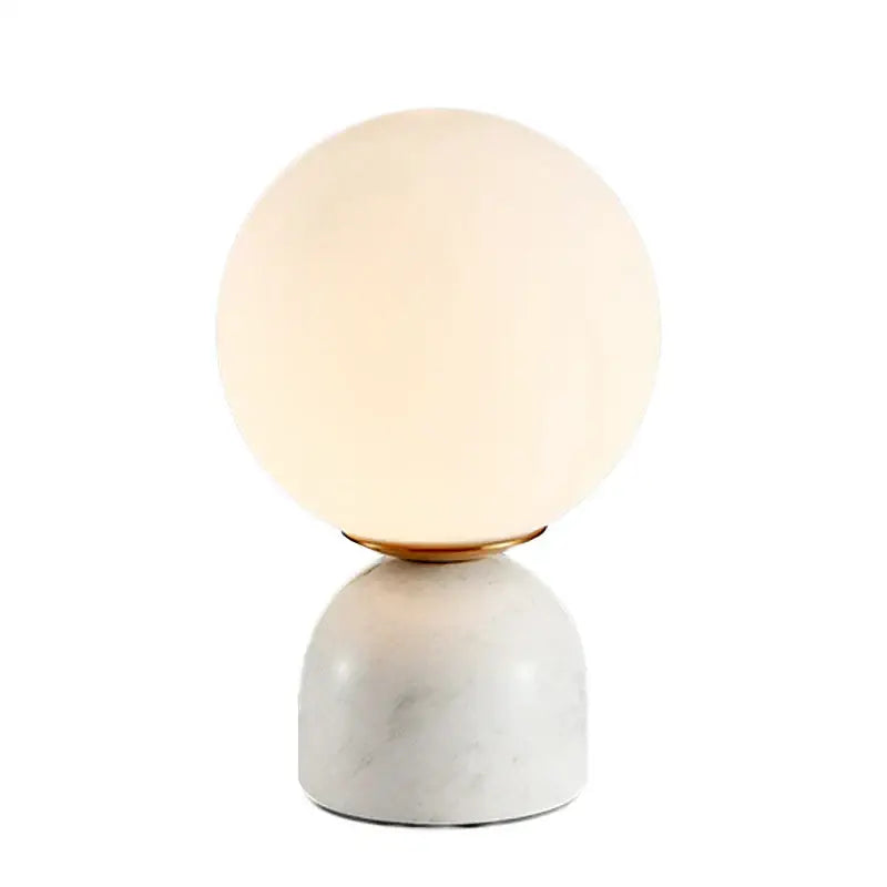 A sleek spherical decorbites led glass ball table lamp with warm glow on white marble base for home lighting