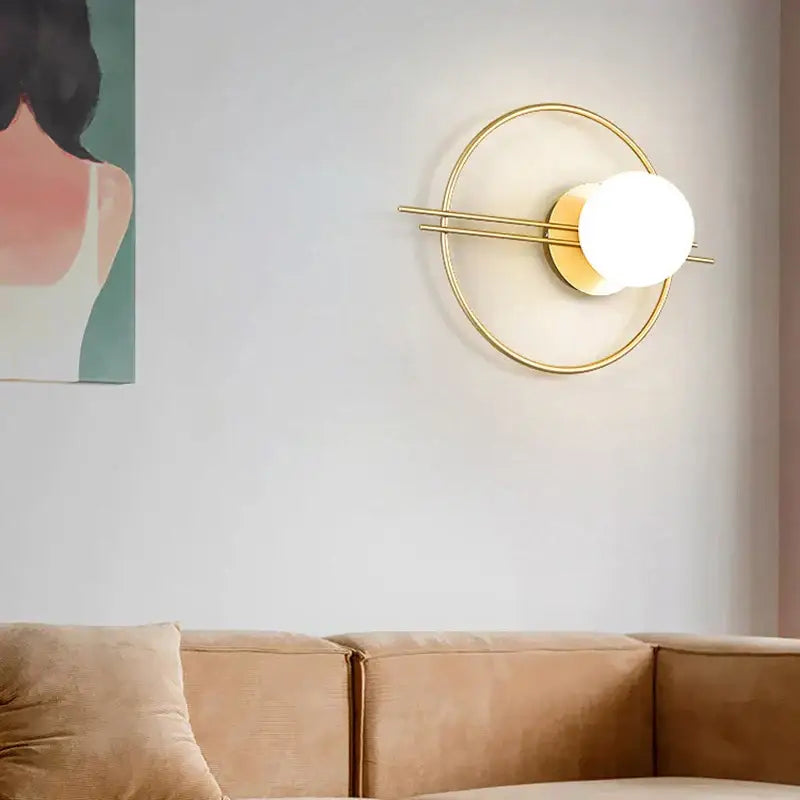 Modern gold-toned decorbites led glass ball wall sconce with glowing white spherical bulb for bedroom or living room