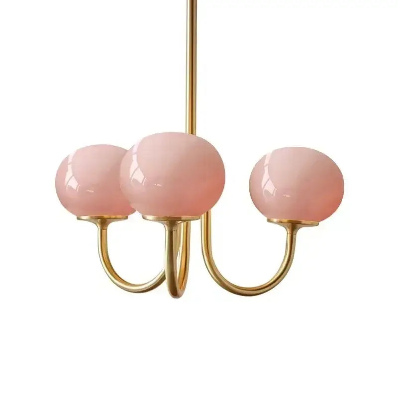 A delicate three-arm DecorBites LED glass balls chandelier with pink translucent globes and polished brass fixtures