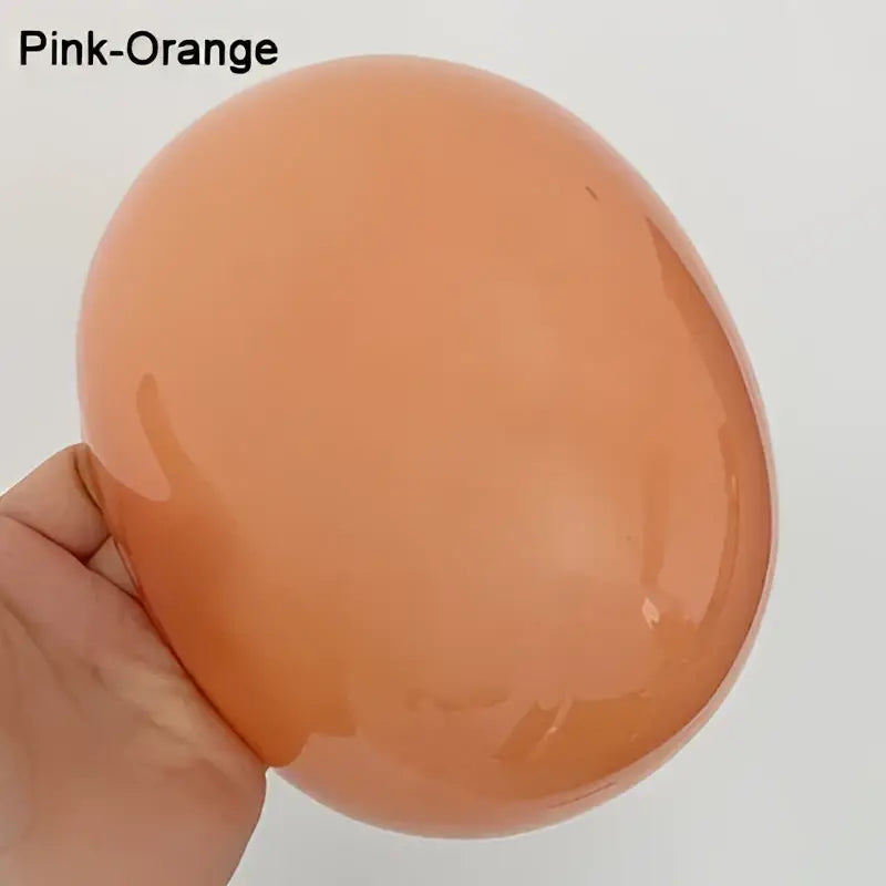 A smooth pink-orange glass ball pendant light held in hand from decorbites led glass balls chandeliers collection