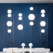 Modern white spherical decorbites led glass beads pendant chandelier with black rods against a deep blue wall