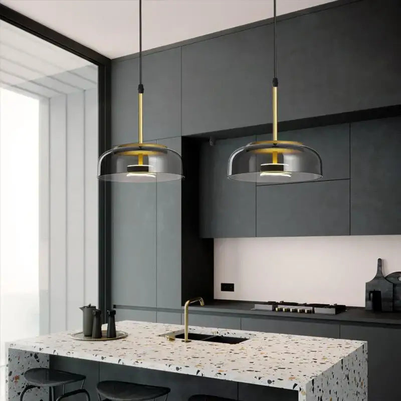 Two decorbites led glass pendant lights with gold rods and translucent led glass bowl shades above kitchen island