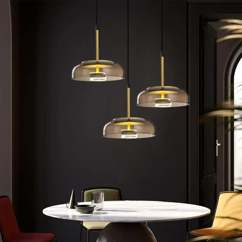 Three modern DecorBites LED glass bowl pendant lights with gold metal stems and smoked glass shades for dining use