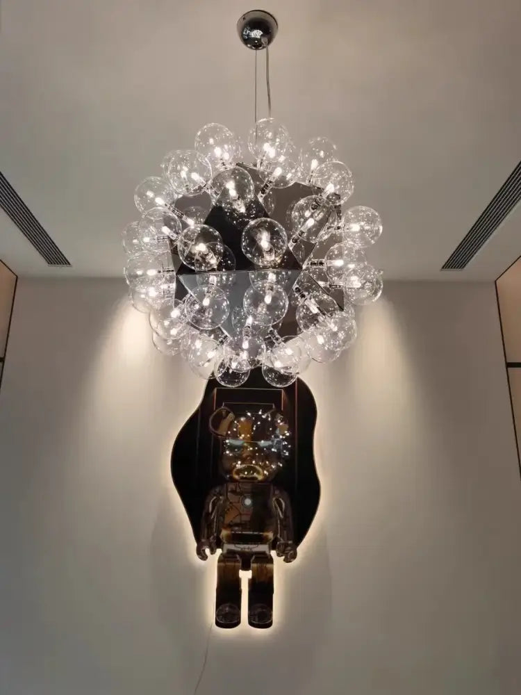 A decorbites led glass bubble chandelier with clear glass bulbs in a chrome finish above a dark bear sculpture