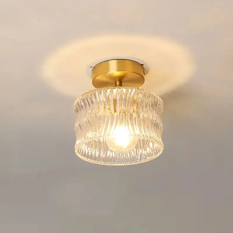 A clear ribbed glass decorbites led glass ceiling lamp with a gold-toned metal base for interior decor