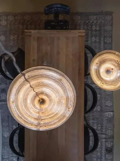 Two amber-tinted circular glass pendant lights of decorbites led glass chandelier hang above a wooden table
