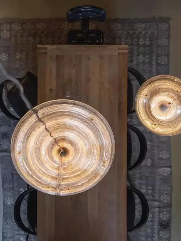 Two amber-tinted circular glass pendant lights of decorbites led glass chandelier hang above a wooden table