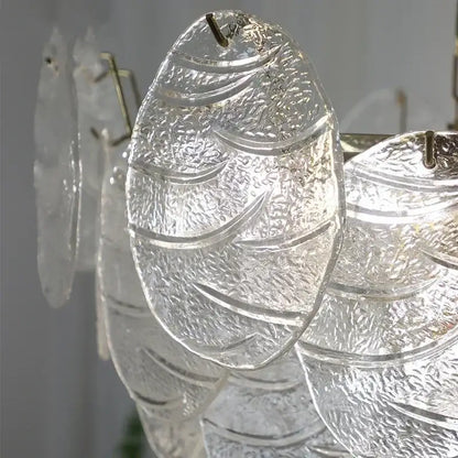 Clear textured glass fish-shaped pendant with intricate etching and metallic hook in decorbites led glass chandelier design
