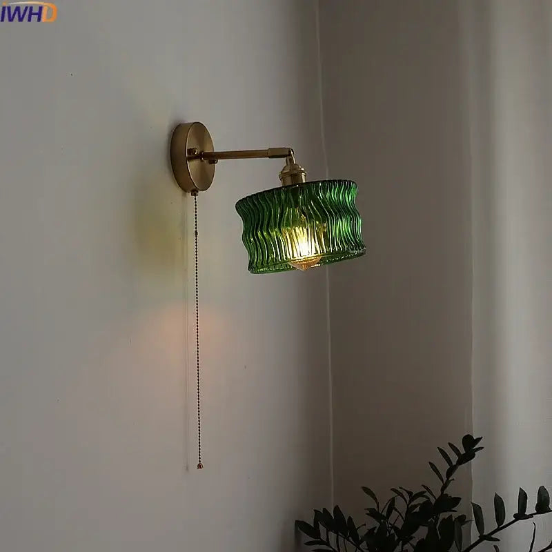 Green ribbed glass wall sconce with brass arm and pull chain switch for bedroom or living room lighting
