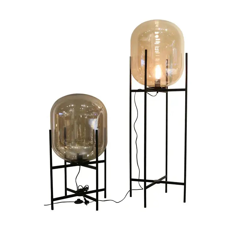 Tall DecorBites led glass floor lamp with black metal frame and amber globe shade in modern minimalist design