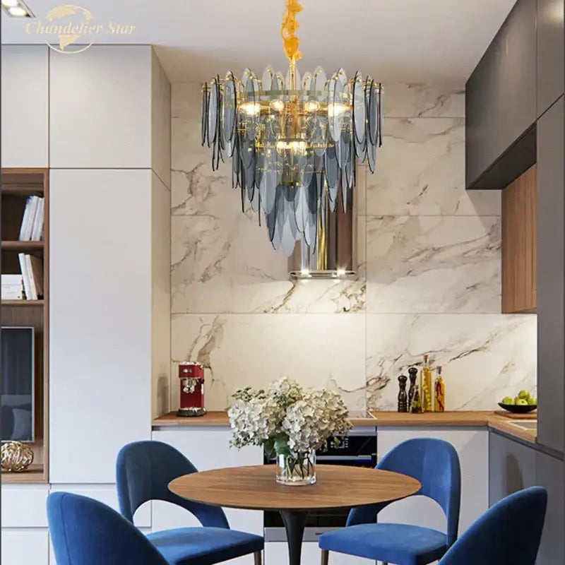 A decorbites led glass metal leaf chandelier with cascading blue and gold glass leaves on a golden frame