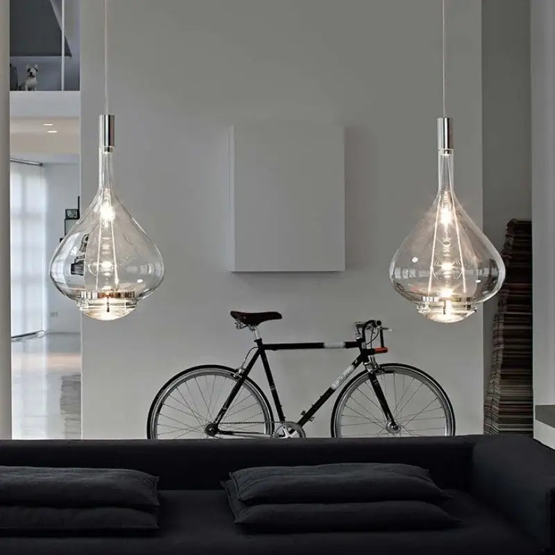 Two clear glass decorbites led glass pendant chandelier lights with metallic fixtures hanging from the ceiling Italy design