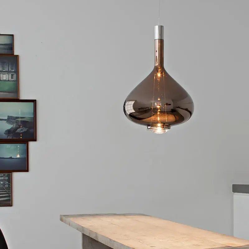 A sleek amber-tinted decorbites led glass pendant chandelier with metallic stem hangs above wooden countertop