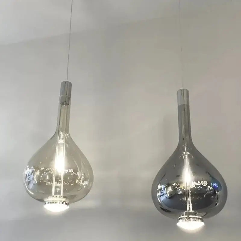Two modern decorbites led glass pendant chandelier lights with clear and mirrored teardrop glass shades hanging on cords