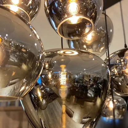 A modern DecorBites™ LED glass pendant chandelier with multiple reflective spherical glass shades for kitchen décor