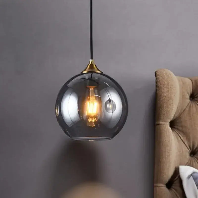 A sleek DecorBites™ LED glass pendant chandelier with smoked glass globe and brass top for kitchen dining bar décor