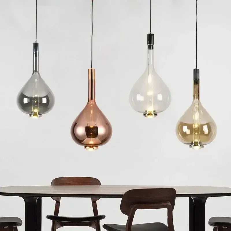Four decorbites™ led glass pendant lamps with teardrop glass shades in silver rose gold clear and amber above dining table
