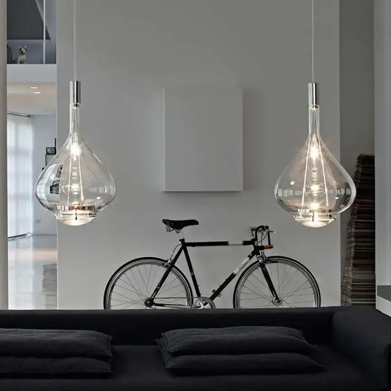 Two elegant teardrop shaped led glass pendant lamps with metallic fixtures for hotel kitchen restaurant bar lighting