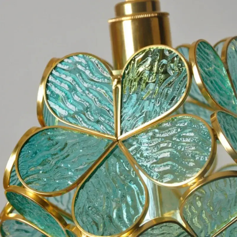 A teal glass clover-shaped perfume bottle with gold accents and textured wavy pattern in decorbites led glass pendant lights collection