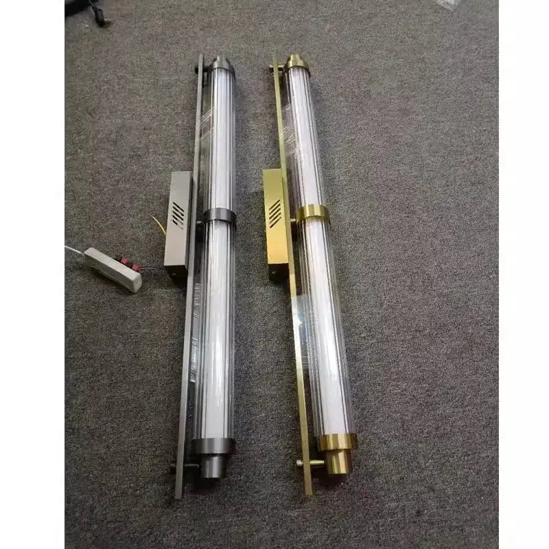 Two modern decorbites led glass wall lamps with brushed nickel and brass finishes featuring clear glass tubes encasing led bulbs