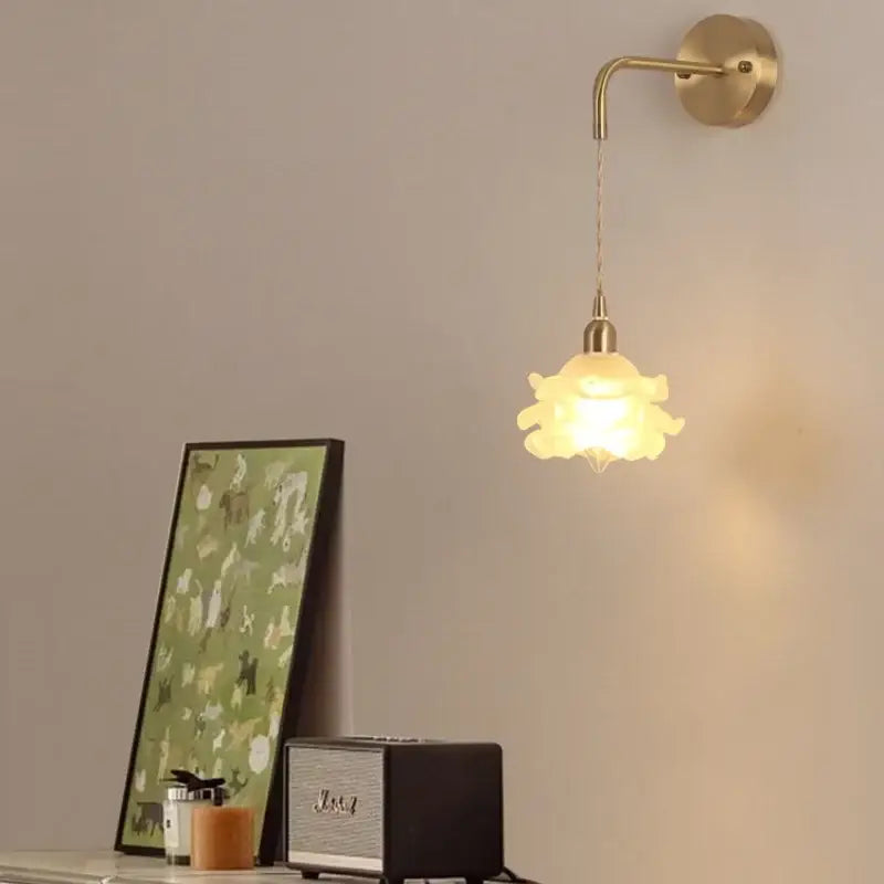 A warm-toned led glass wall lamp with petal design and brass mount by decorbites for modern bedroom decor