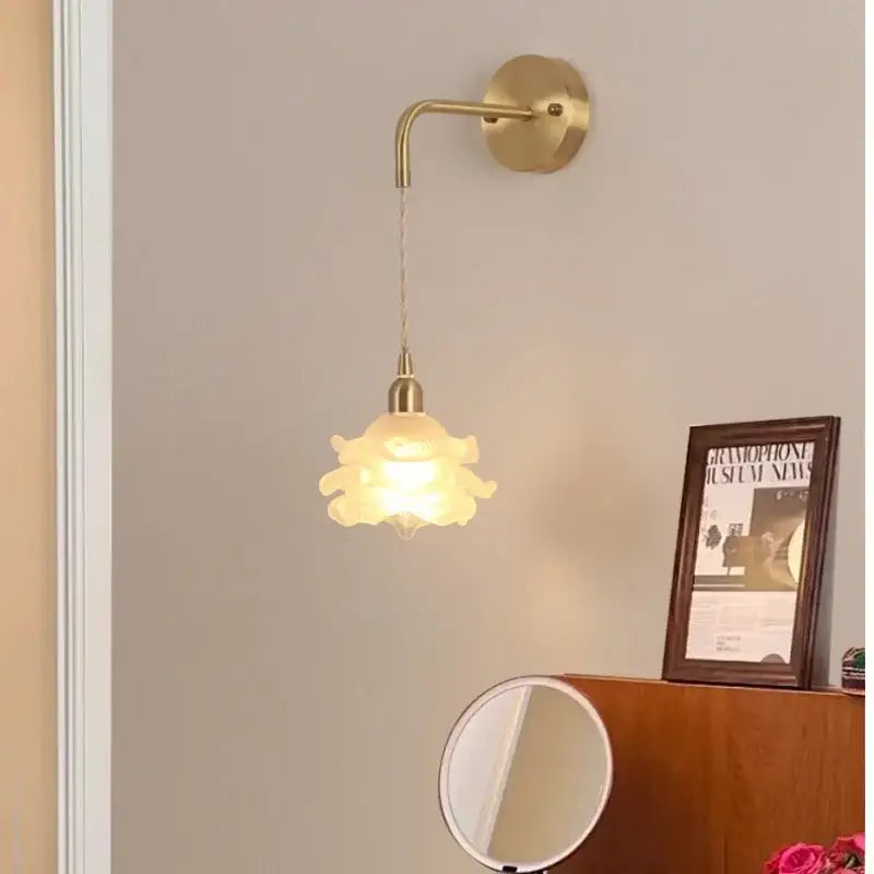 A delicate brass decorbites led glass wall lamp with a frosted flower-shaped shade for modern bedroom use