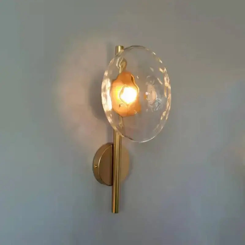A modern wall sconce with a gold metal base and clear textured glass shade from decorbites led glass wall sconce series