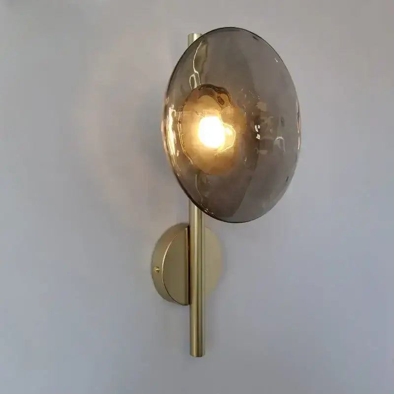 A modern decorbites led glass wall sconce with brushed brass finish and amber glass shade for living room lighting